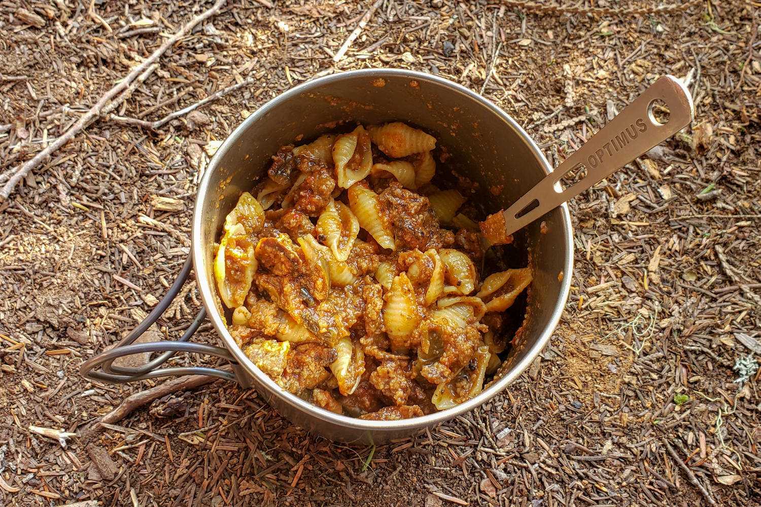 pot of noodles and ground beef in a red sauce in a backpacking pot
