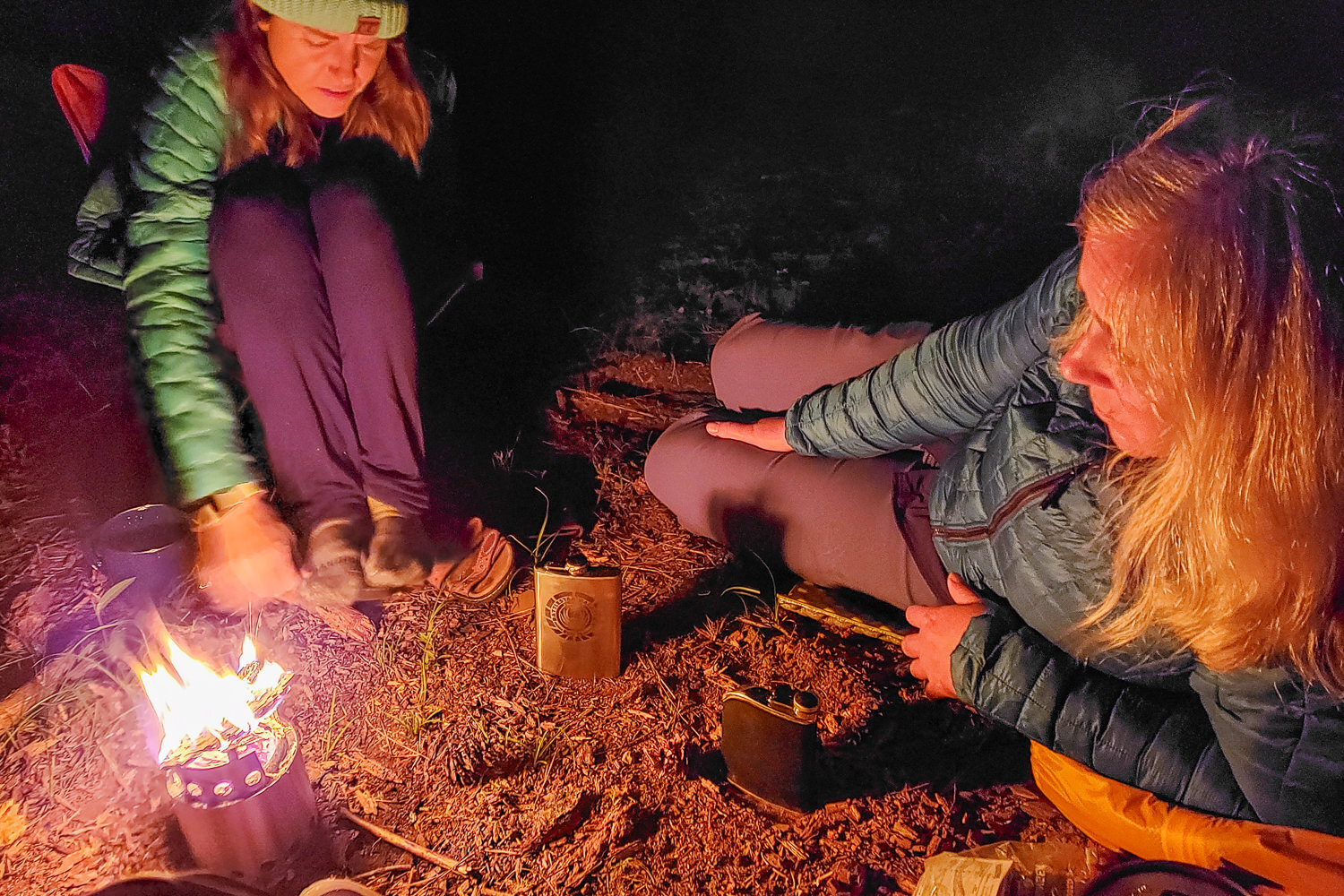 two campers sitting by a small solo stove