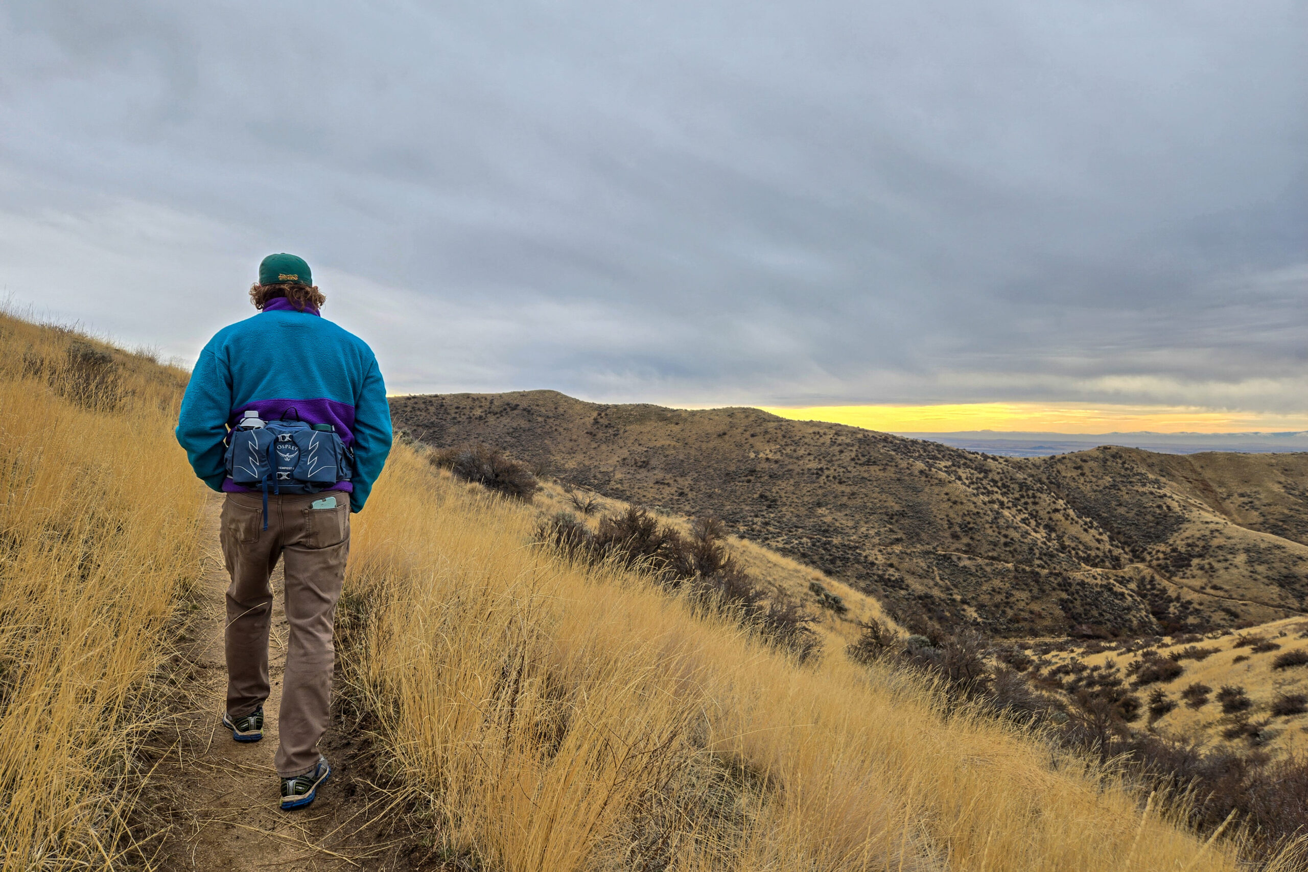 man walking on a trail in the high desert wearing a fanny pack