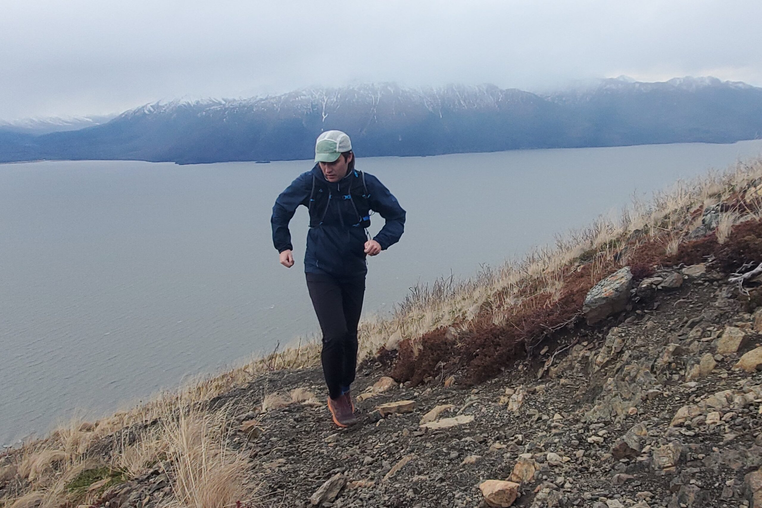A man runs up a steep trail above the ocean.
