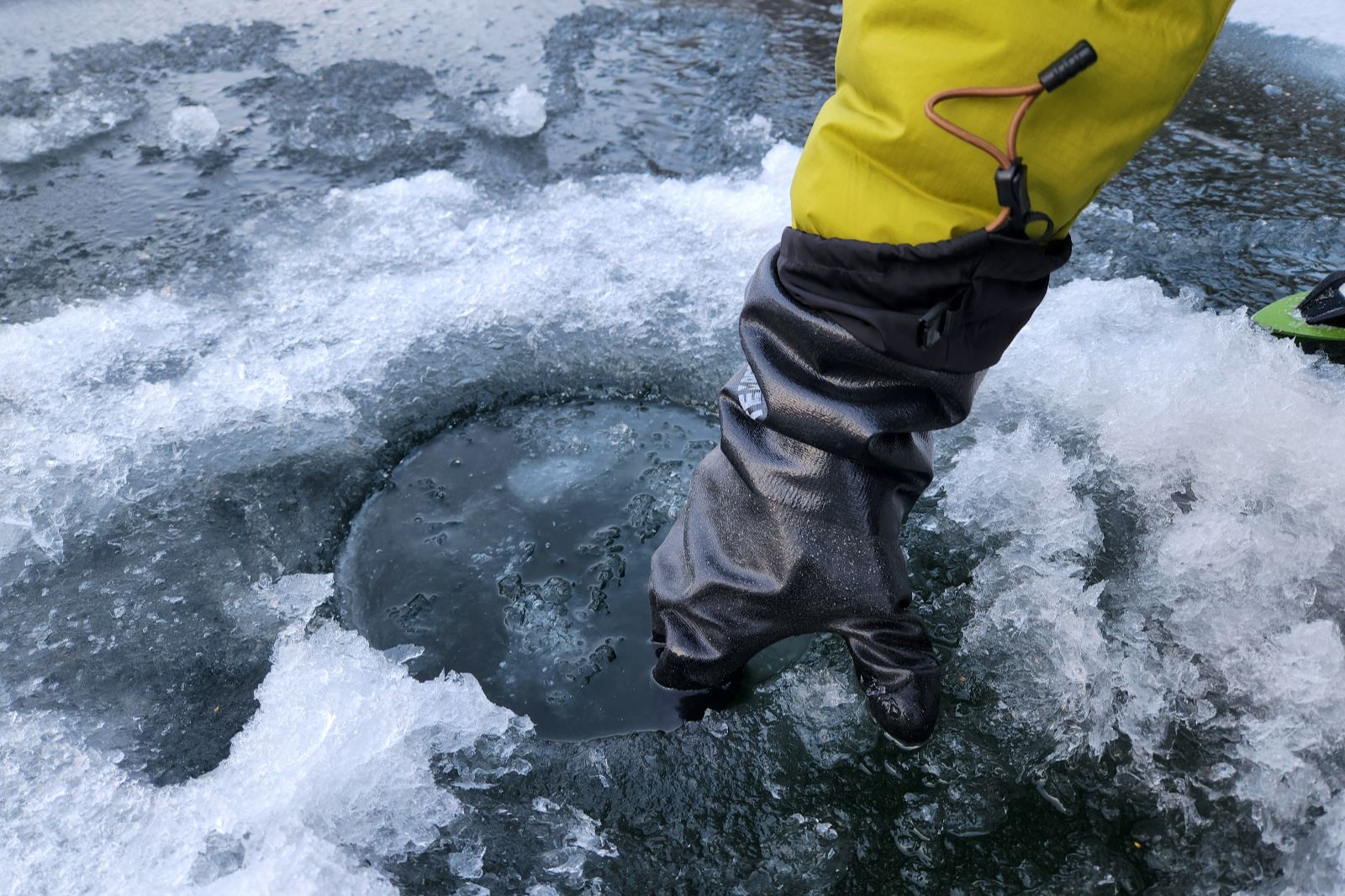 A pair of black gloves half-submerged in icy water.