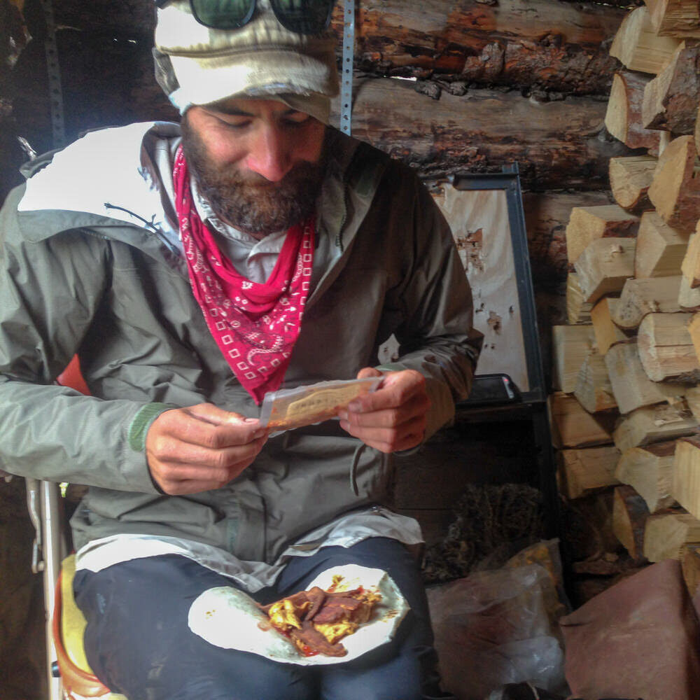 backpacker assembles a wrap in a leanto