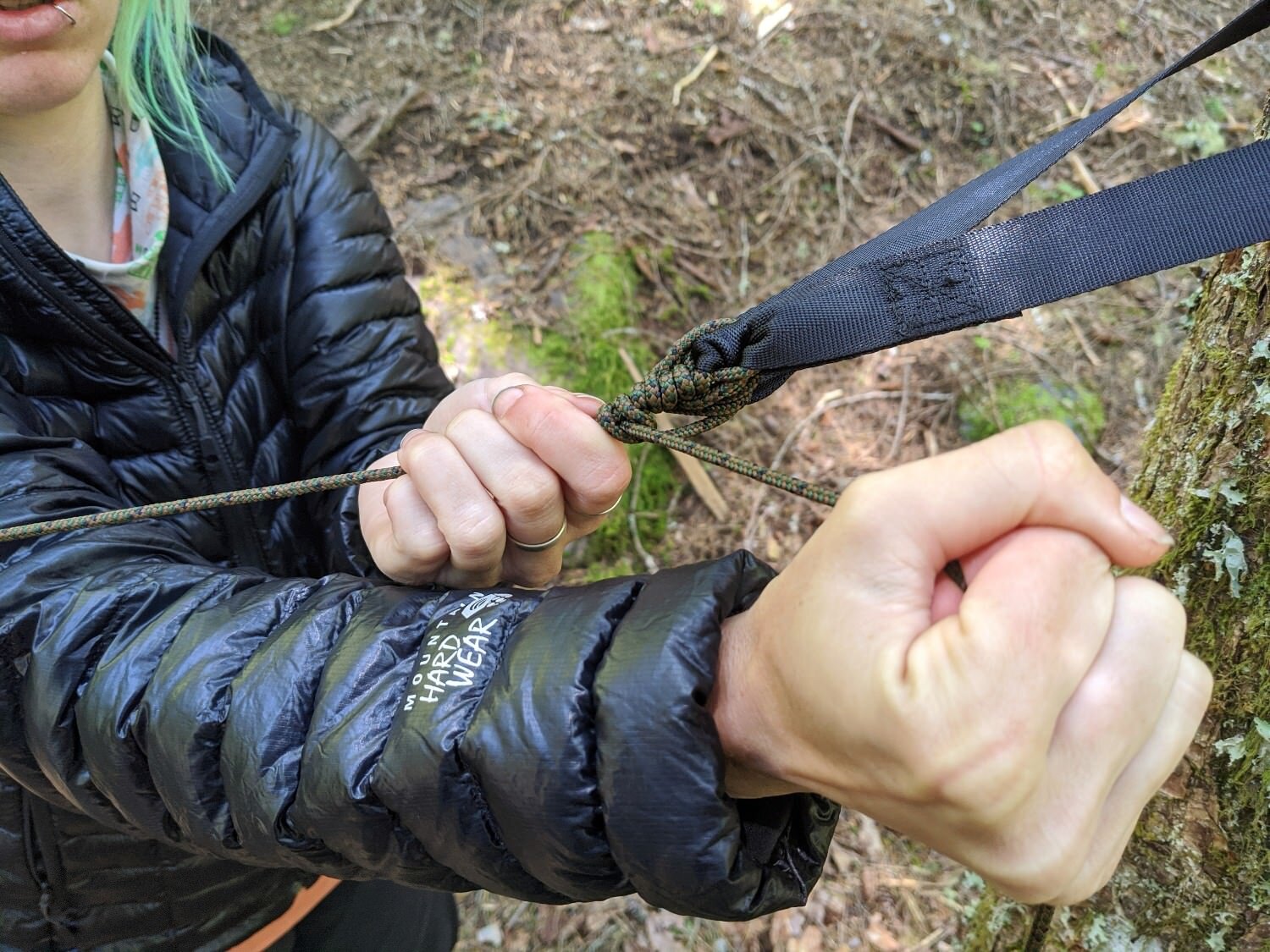 A hiker tying a knot in the Hennessy Ultralight Backpacker Hammock suspension system