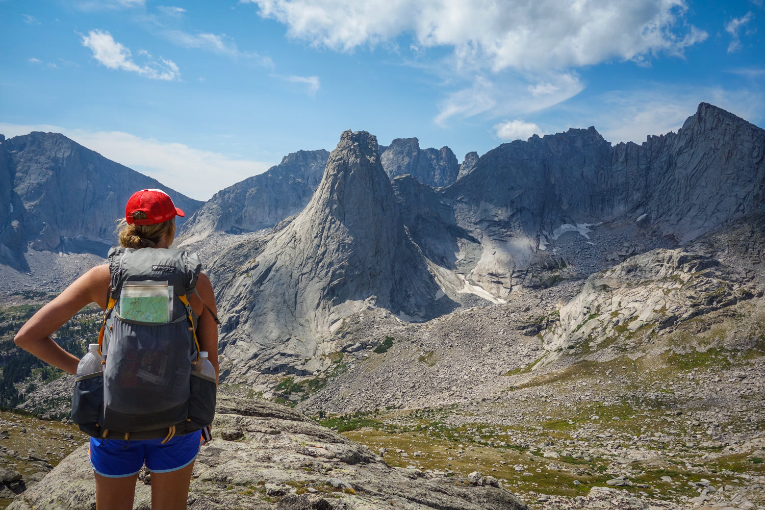 A hiker wearing the Gossamer Gear Gorilla backpack looking at some large mountains in the distance