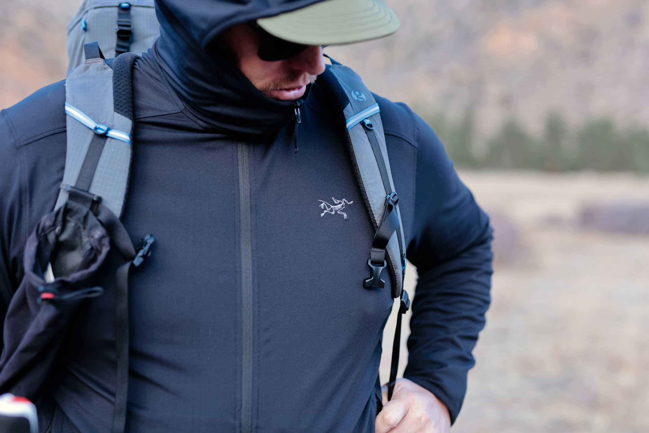 Man wears a backpack and looks down at the trail.