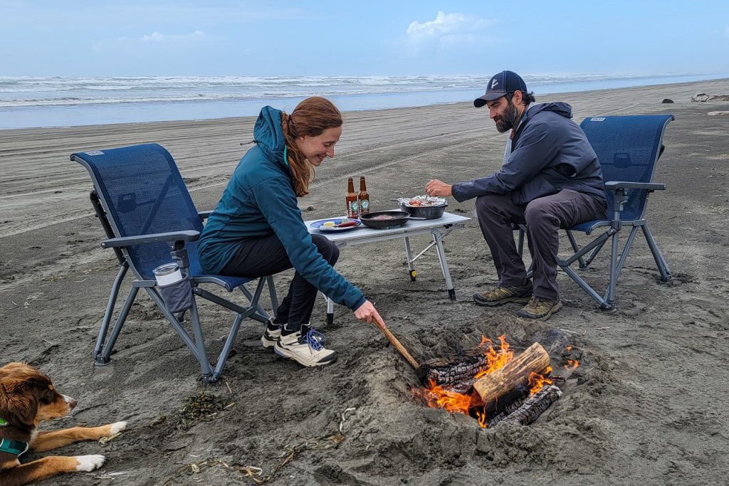 two people enjoy a fire on the beach