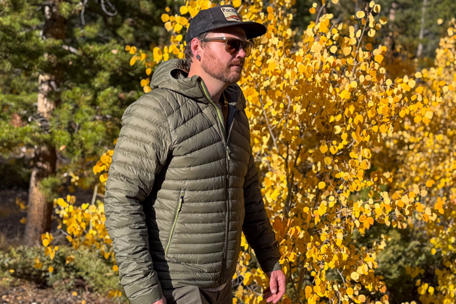 A person wearing the olive Simond MT100 Down Jacket walks through bright yellow fall foliage, showcasing the jacket in seasonal use.