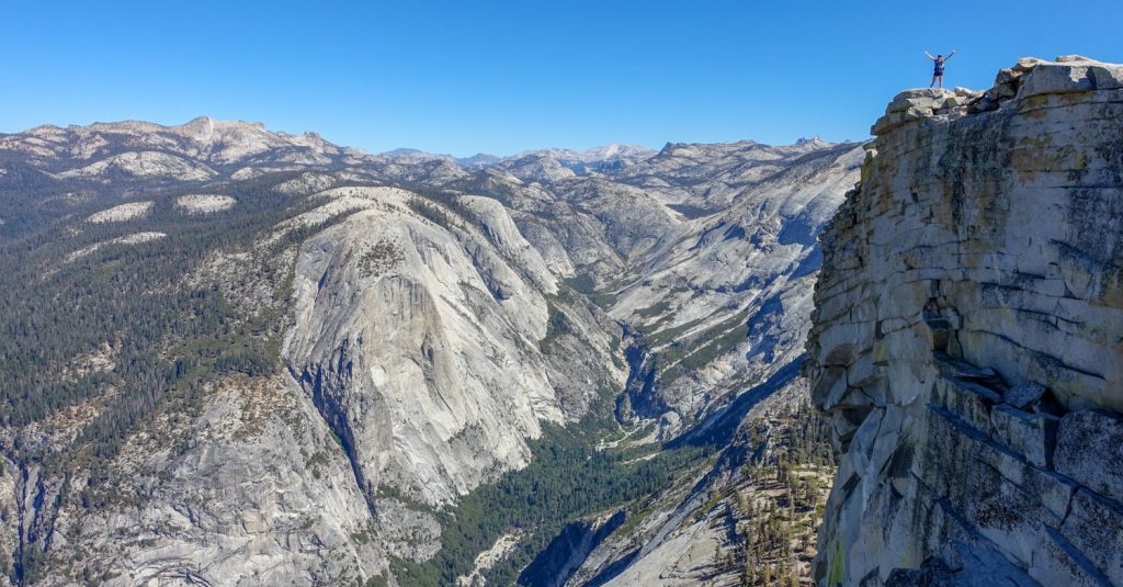 hiker standing on top of half dome in yosemite national park