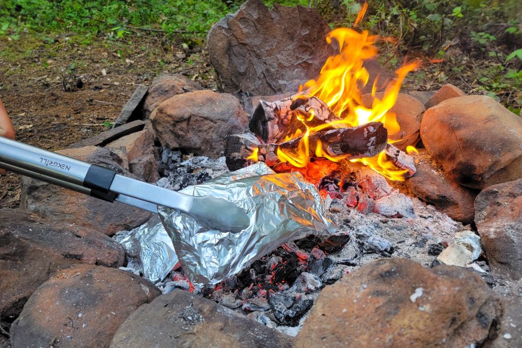 campfire with foil packet meals being cooked