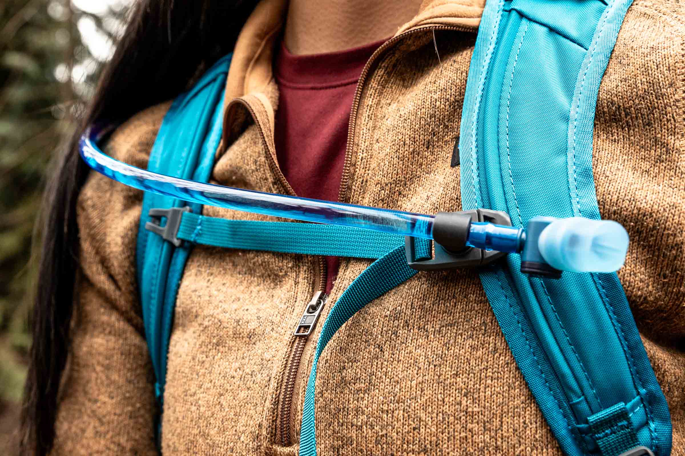 Details of Gregory Swift 16 H2O - a close up view of a person wearing the pack showing the front straps and hydration hose