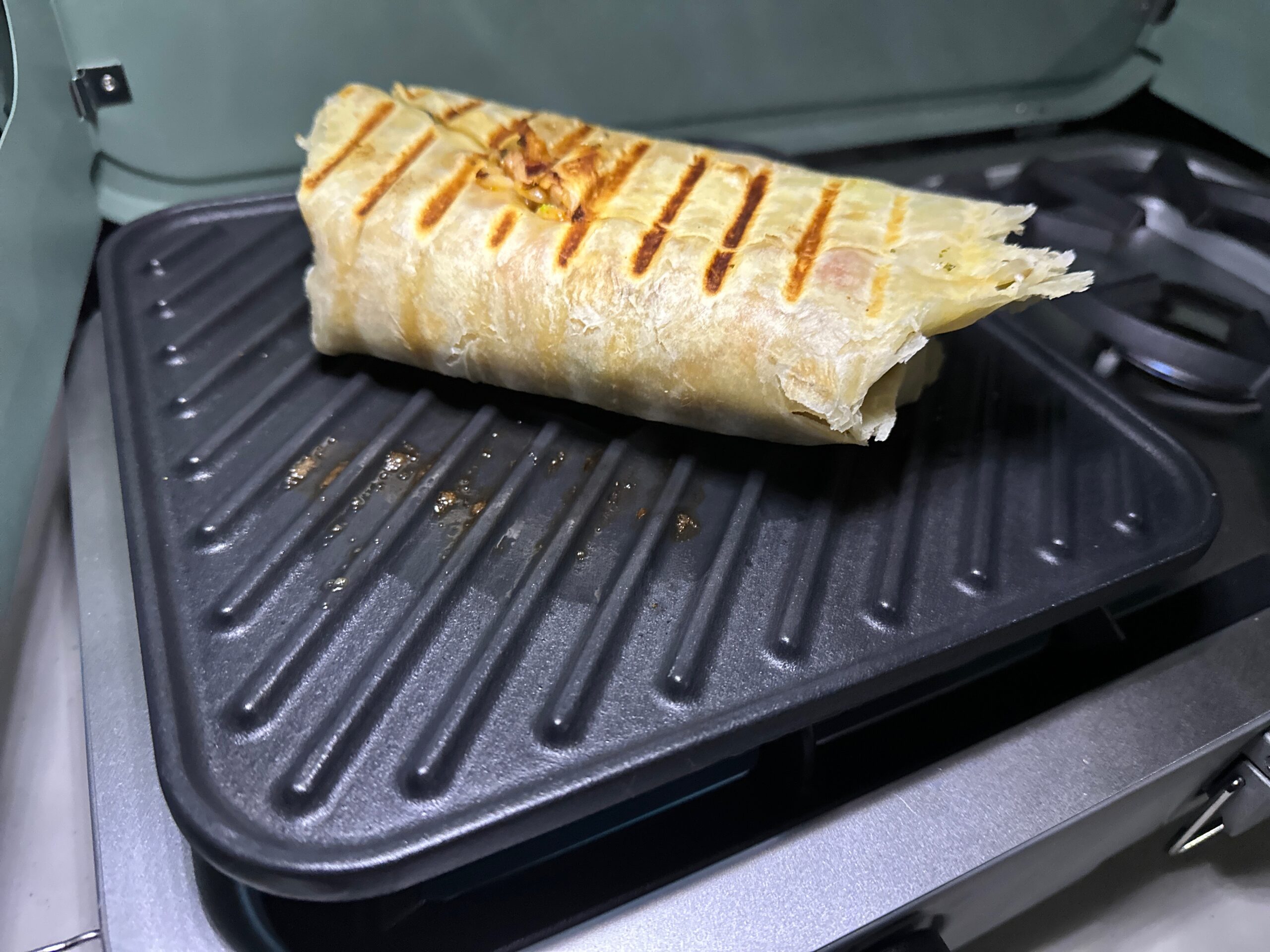 Blue camp stove at forested camp site making rice, burritos, and breakfast.