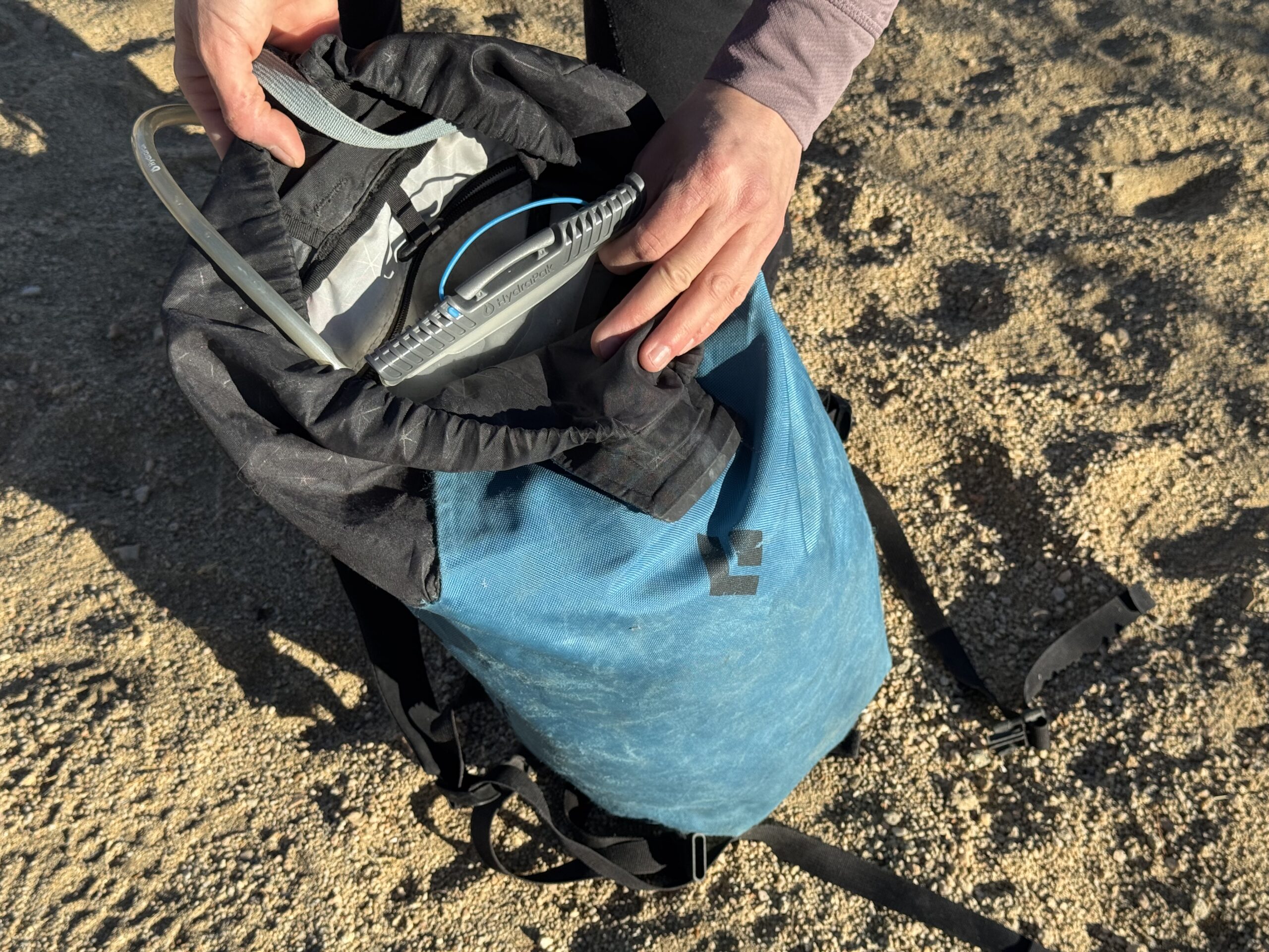 Close up image of hiker loading the HydraPak Contour bladder into a backpack. The backpack doesn't have a hydration sleeve or suspension strap, so the bladder just flops in the bottom.