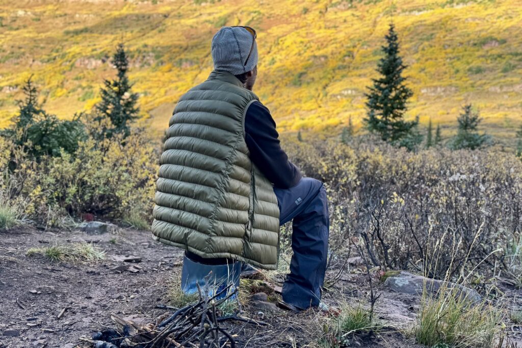 a hiker stares longingly into the distance while sitting on a short bear canister