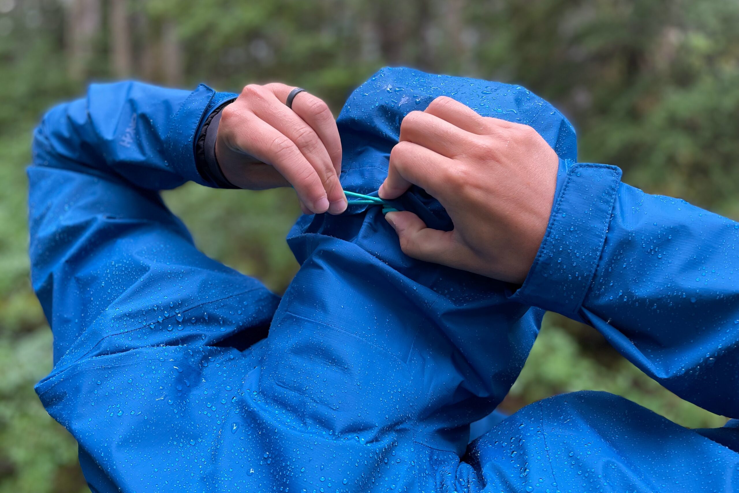 A man adjusts the hood of his rain jacket