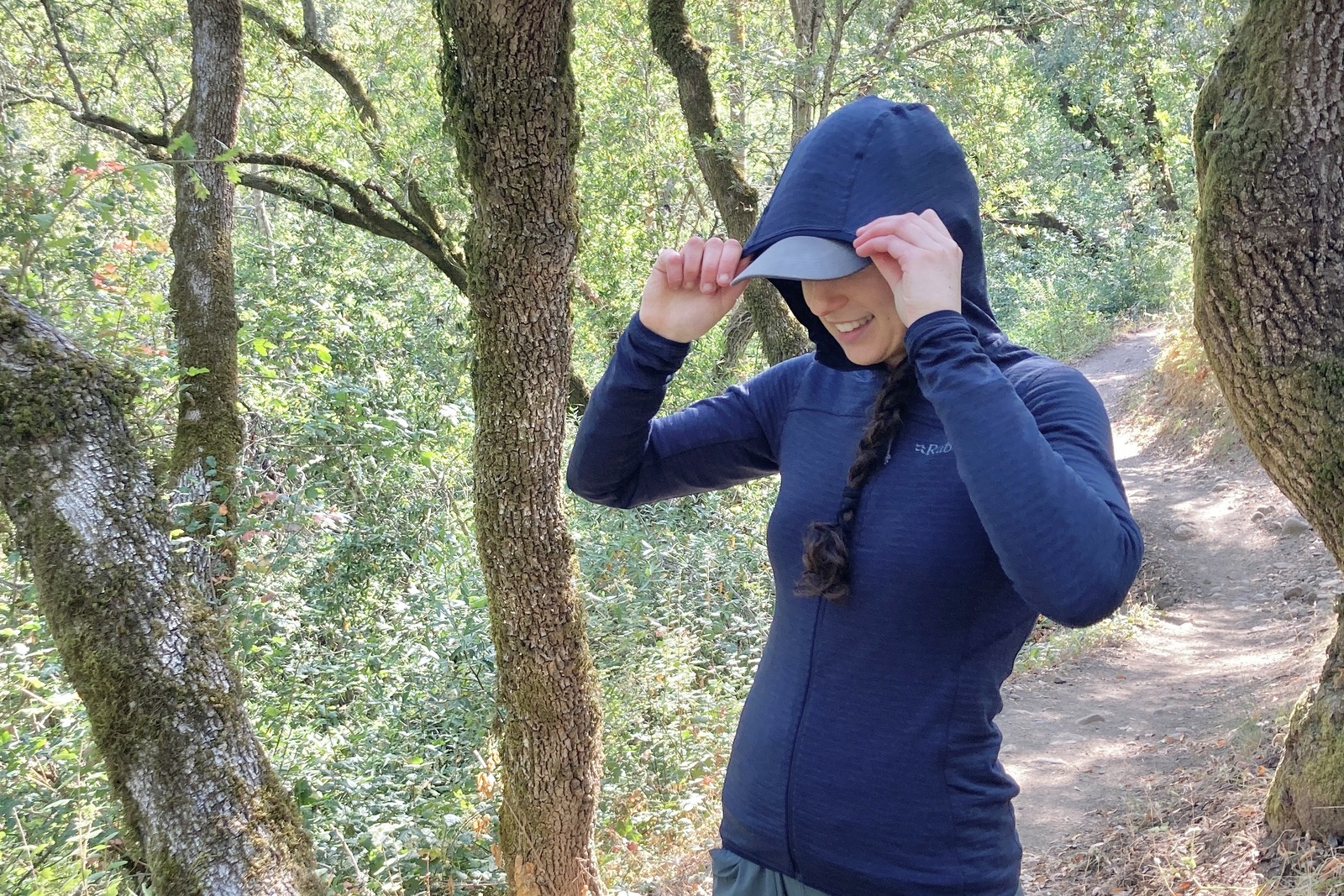 A woman pulls the hood of a fleece jacket over her hat.