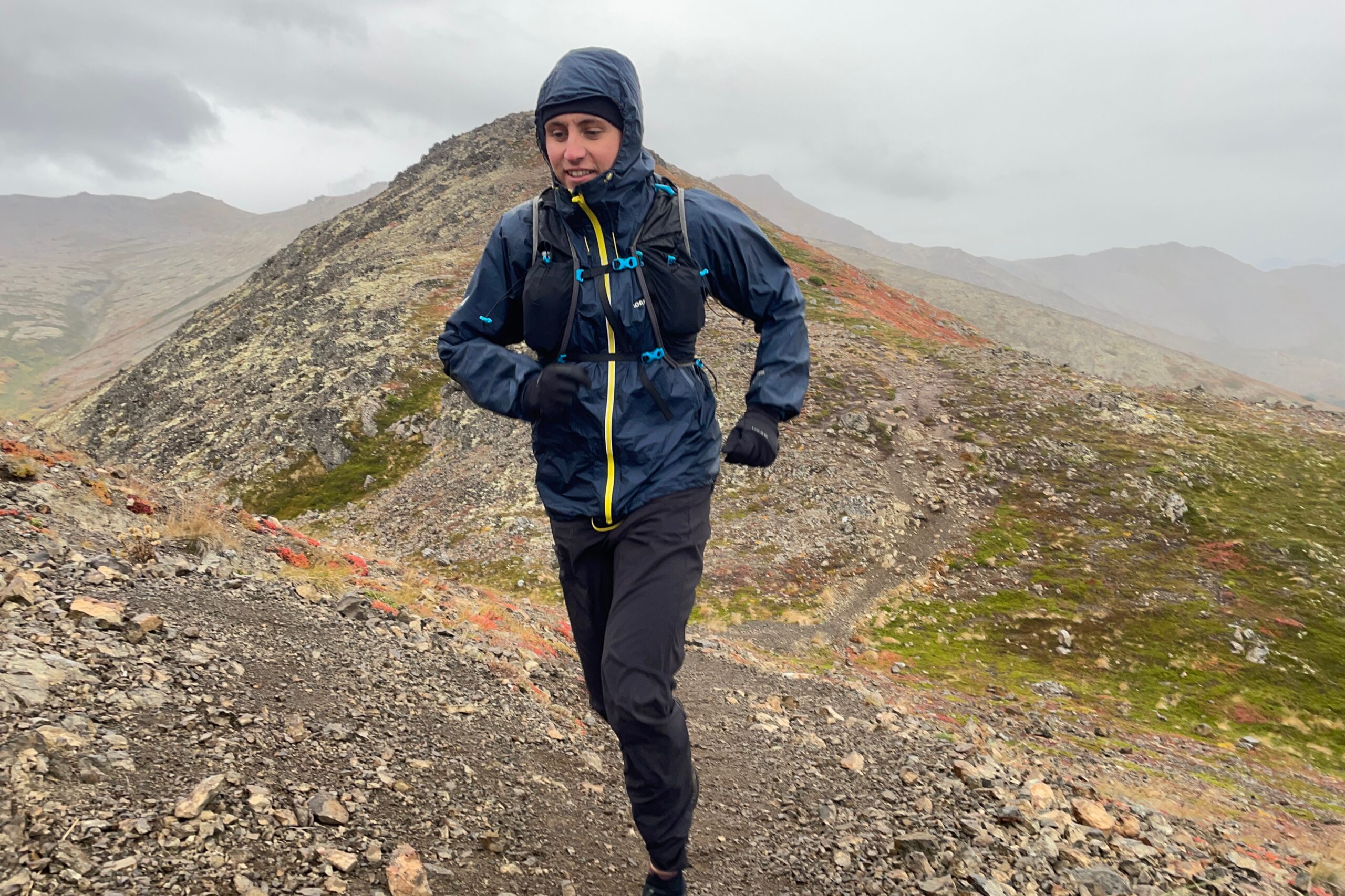 A man runs uphill wearing a rain jacket.
