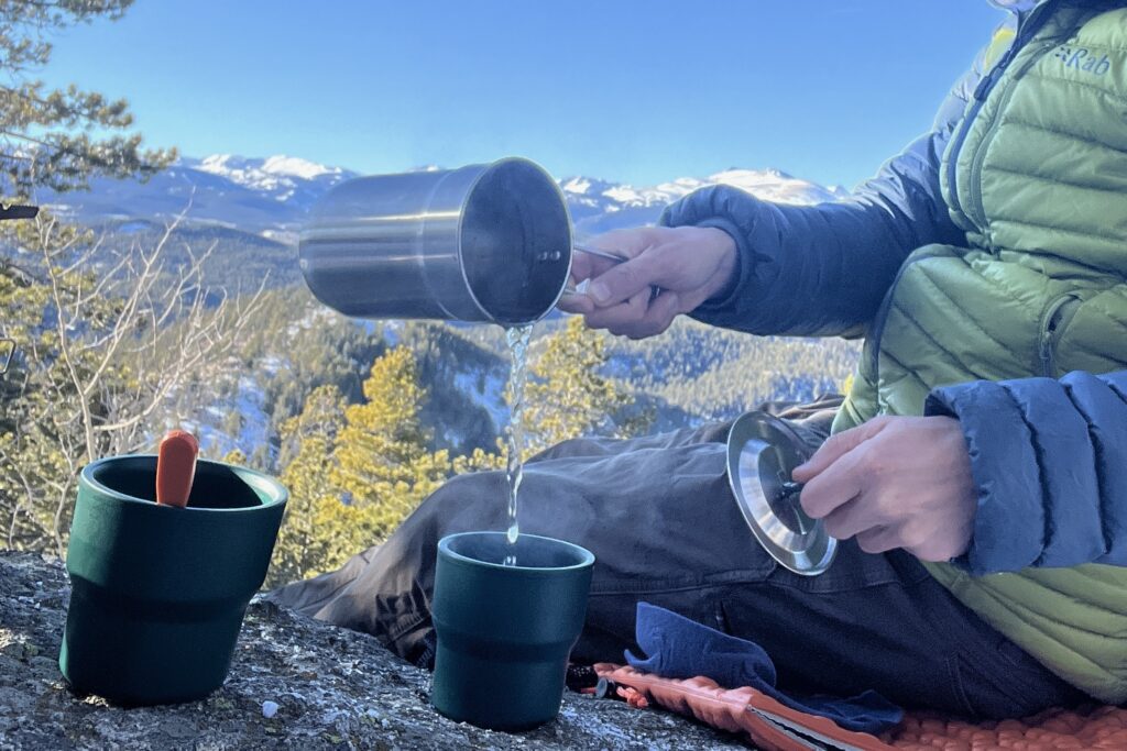 backpacker pouring water into bowl outdoors