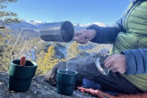 backpacker pouring water into bowl outdoors