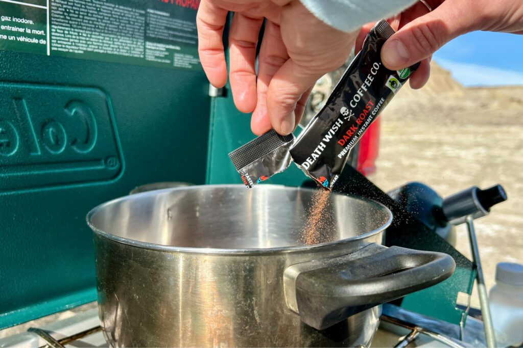 Up-close image of a person pouring instant coffee out of a packet into a pot