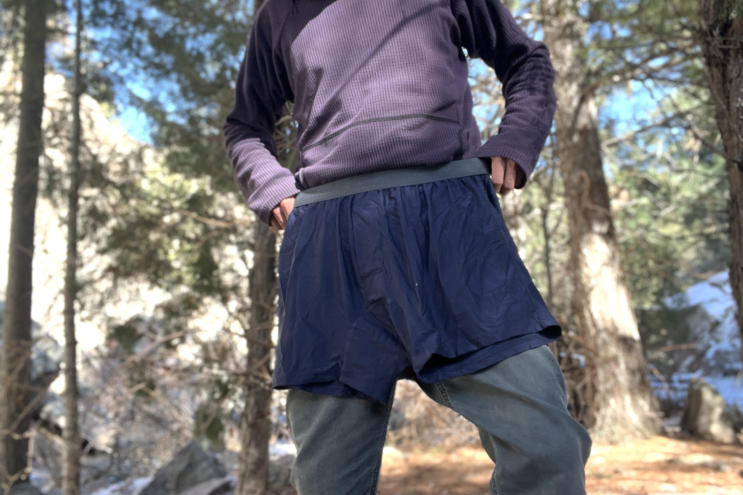A hiker holds a pair of exofficio underwear against himself in a forest.