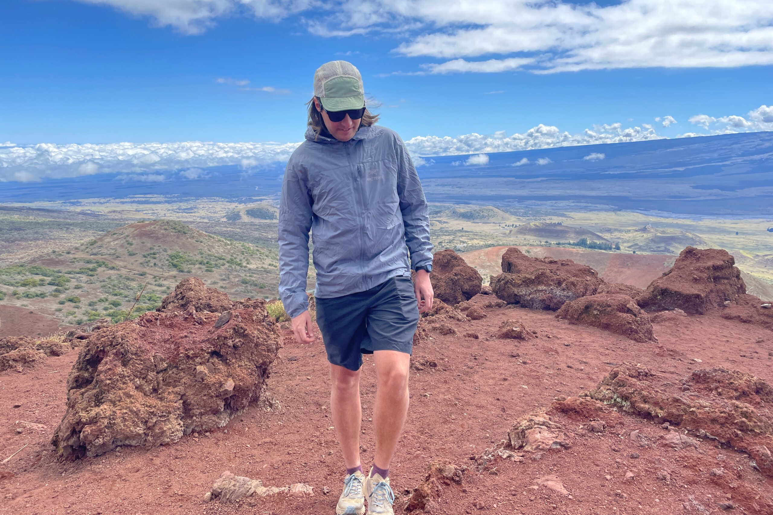 A man walks along an alpine ridge wearing a windbreaker.