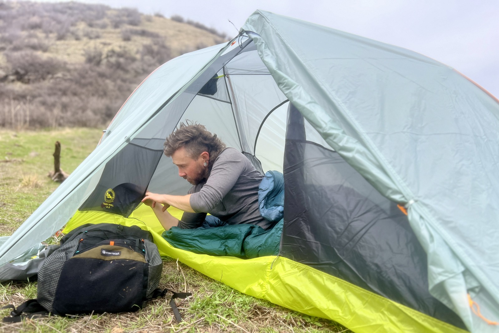 a hiker lays in a tent and sorts through the side pockets