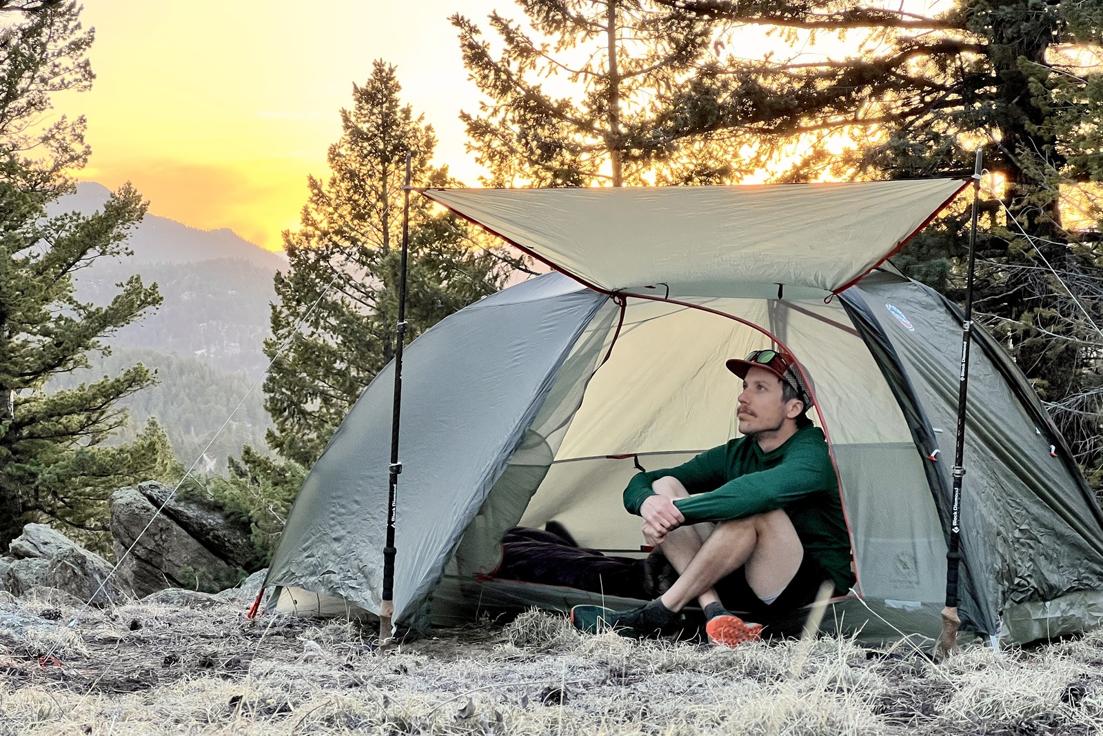 a hiker sits in a tent with the awning deployed during sunset