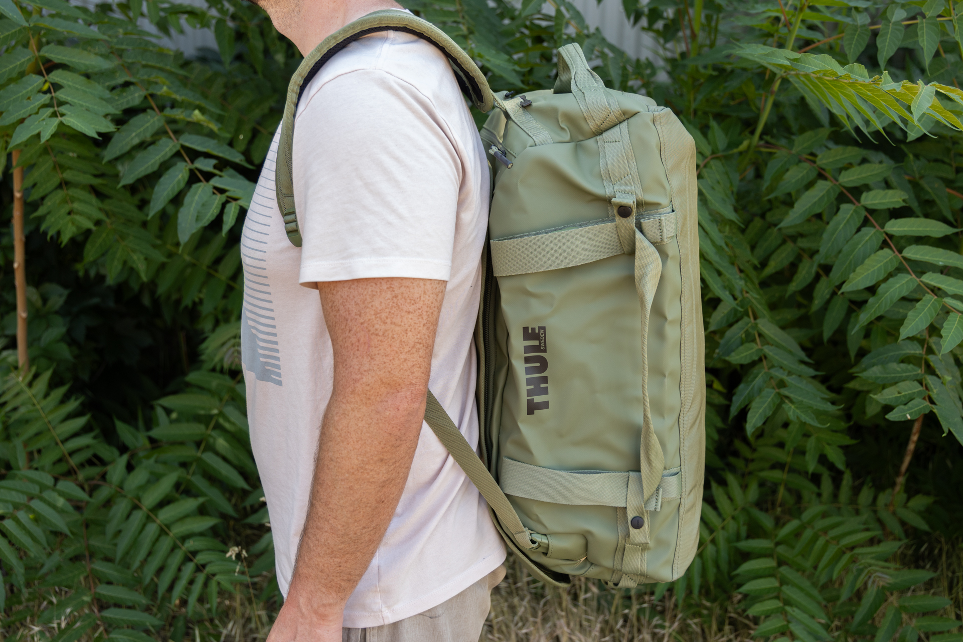 A man wears the Thule Chasm 40L as a backpack. You can see the padded straps and profile of the duffel from the side.