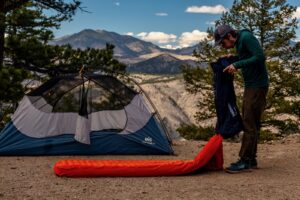 a hiker blowing air into a sleeping pad pump sack