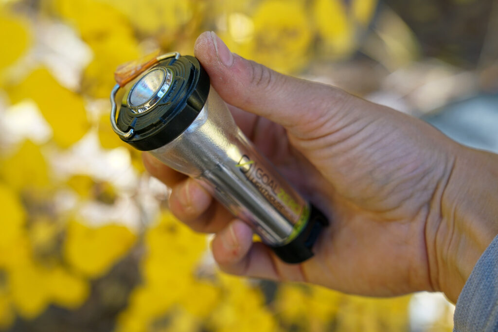 A hand holds the GoalZero Lighthouse Micro Flash lantern with the flashlight pointed up.