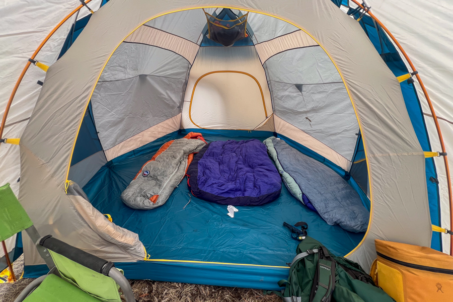 A photo looking into the body of a tent with three sleeping bags placed on the floor of the tent.