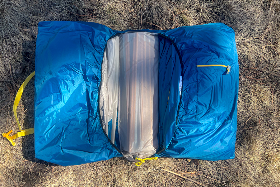 A tent carry-bag laying in brown grass.
