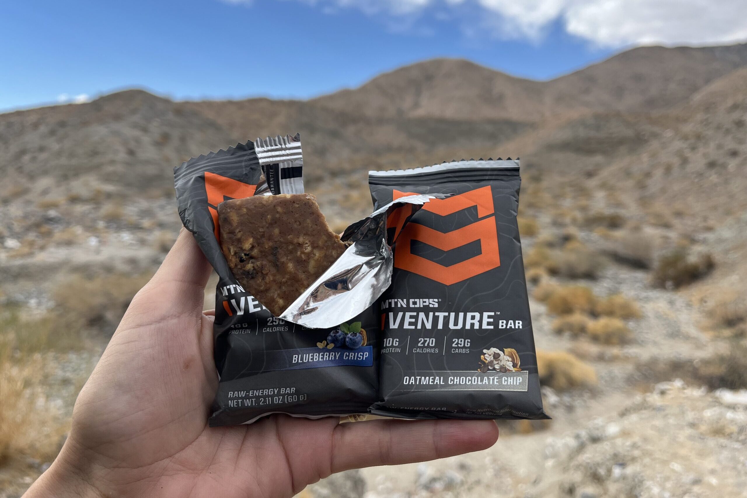 hand holding MTN OPS energy bars in mountainous setting