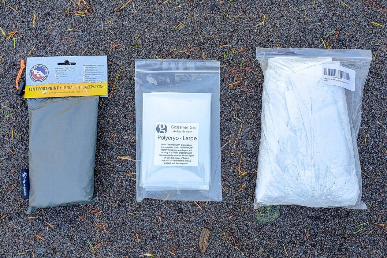 Tent footprint for the Big Agnes Copper Spur, Gossamer Gear Polycryo ground sheet, and a Tyvek ground sheet side-by-side on the sand