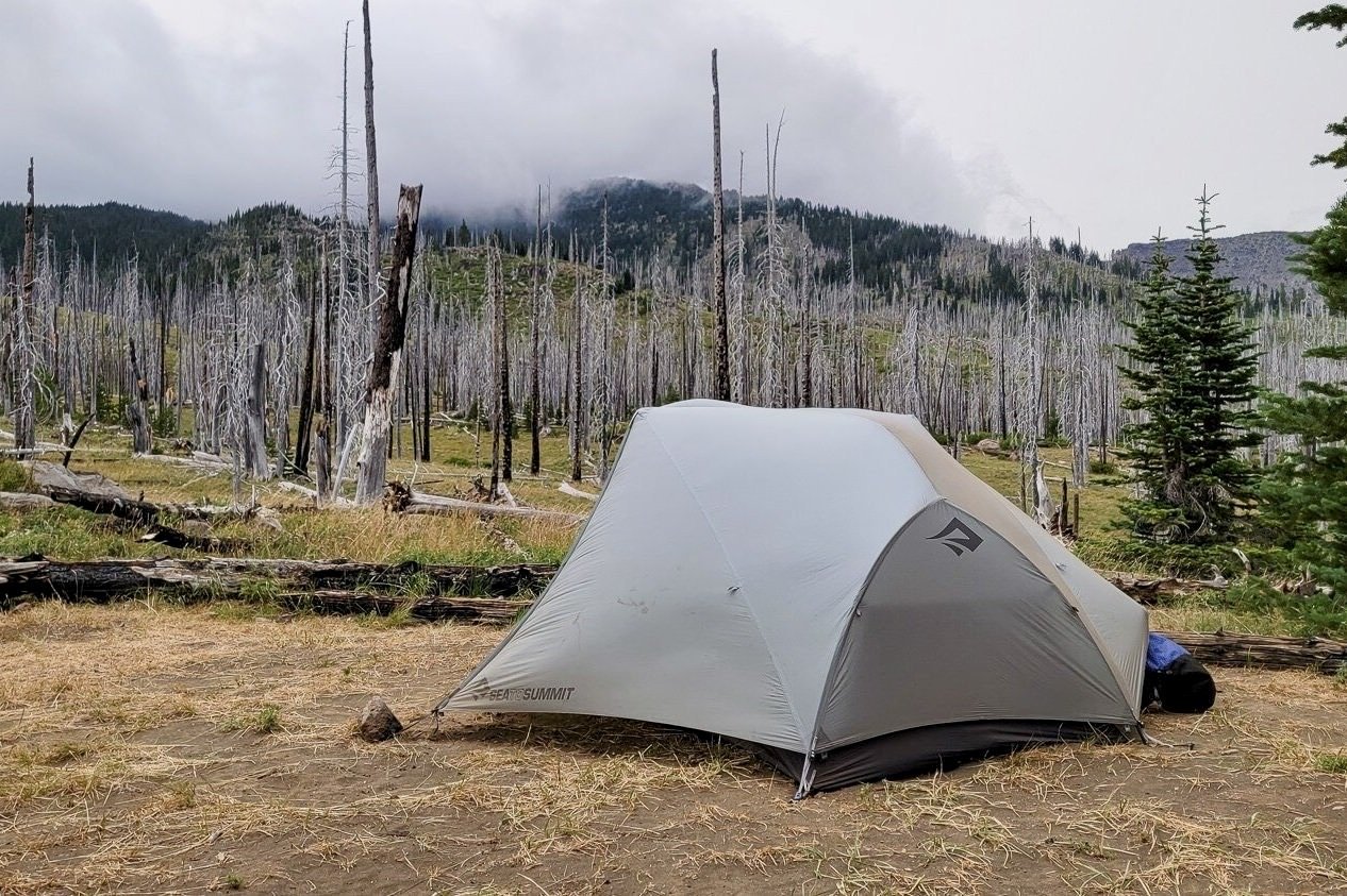 The Sea to Summit Telos TR2 backpacking tent set up in a windy campsite with burnt trees in the background