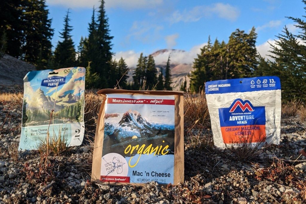 Three freeze-dried macaroni and cheese meals on the ground in their packaging