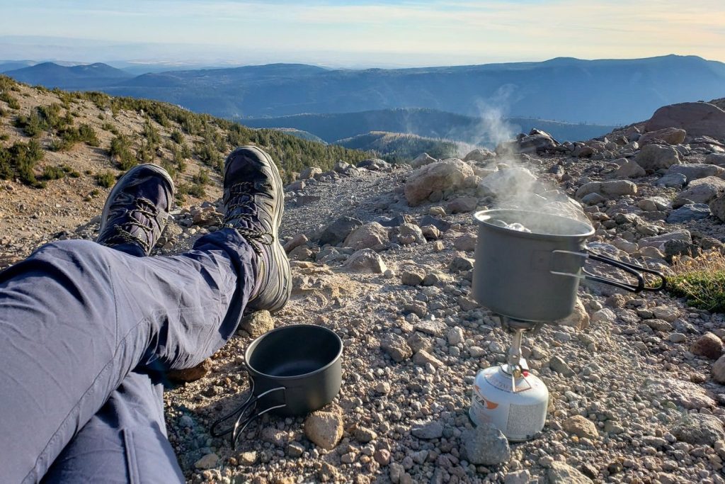 camper cooking a meal with a backpacking stove